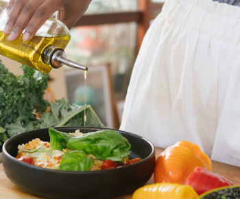 man dressing salad with oil